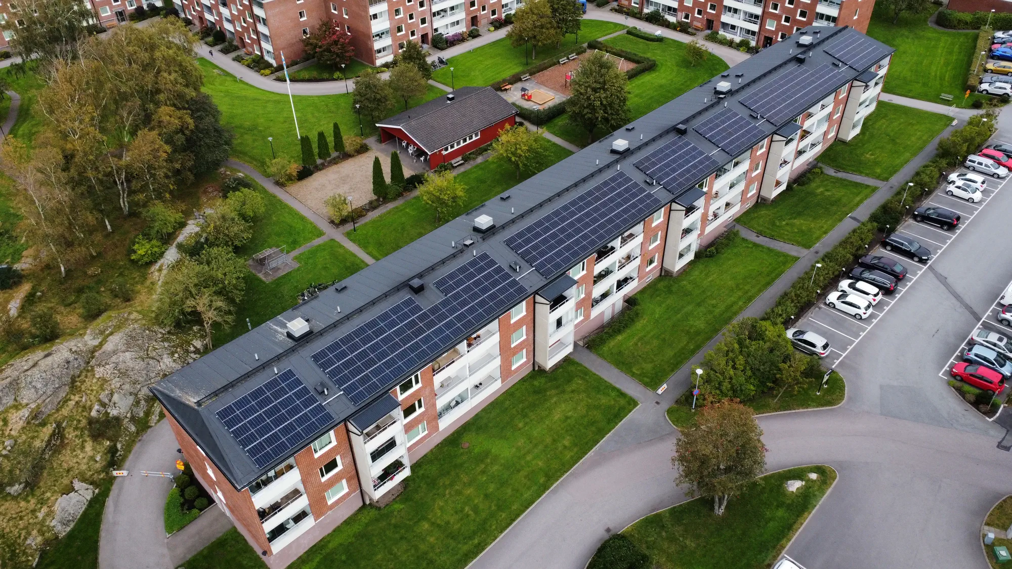 Lång rad av solpaneler installerade på taket av ett stort flerfamiljshus i tegel.