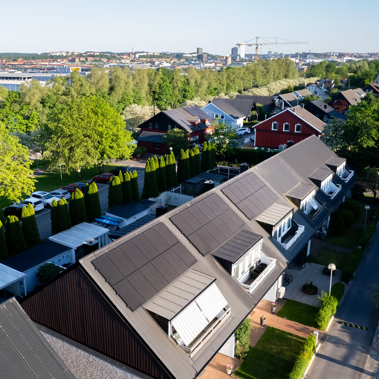 Radhuslänga med integrerade svarta solpaneler på taken med en stadssiluett i bakgrunden.