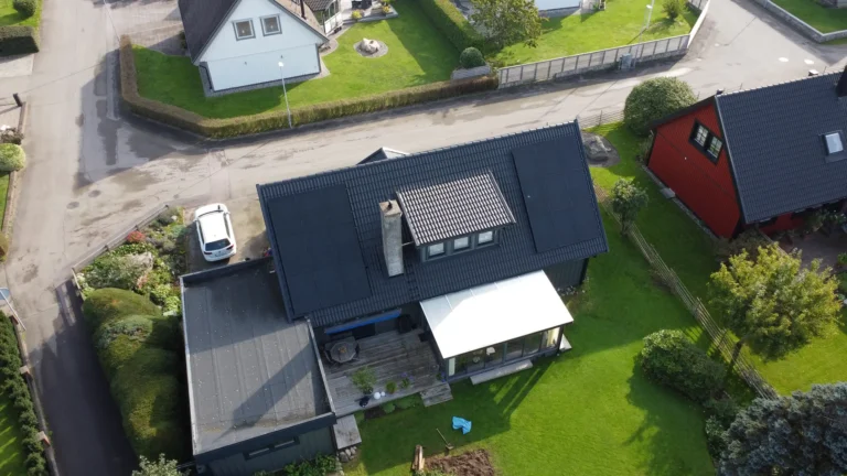 Mörka solceller som smälter in på det svarta taket av en mörkgrå villa.