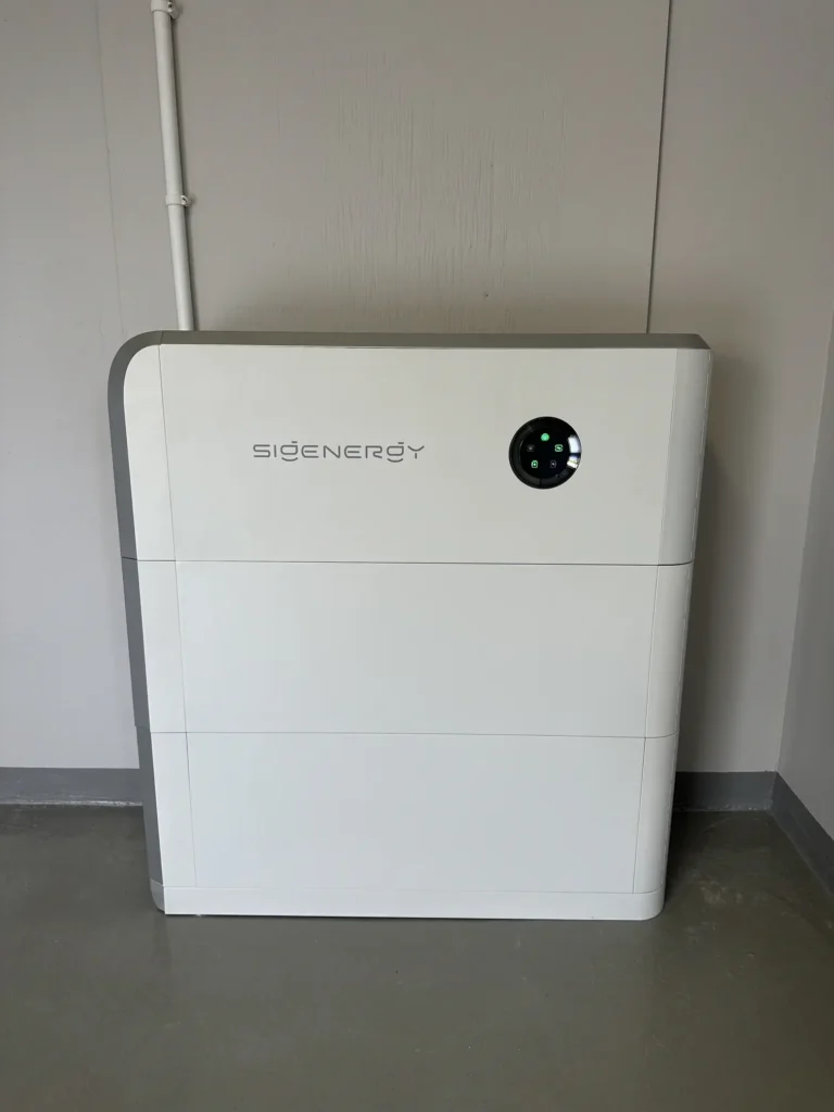 Ett fristående, vitt Sigenergy solcellsbatteri placerat på ett betonggolv inomhus mot en ljus vägg