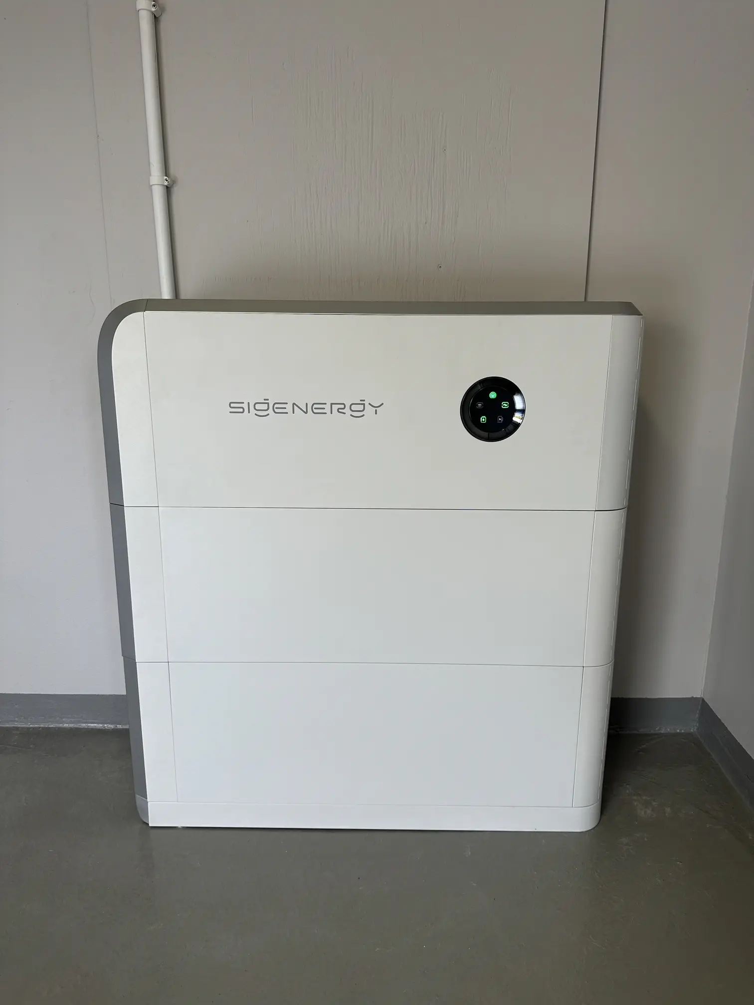 Ett fristående, vitt Sigenergy solcellsbatteri placerat på ett betonggolv inomhus mot en ljus vägg