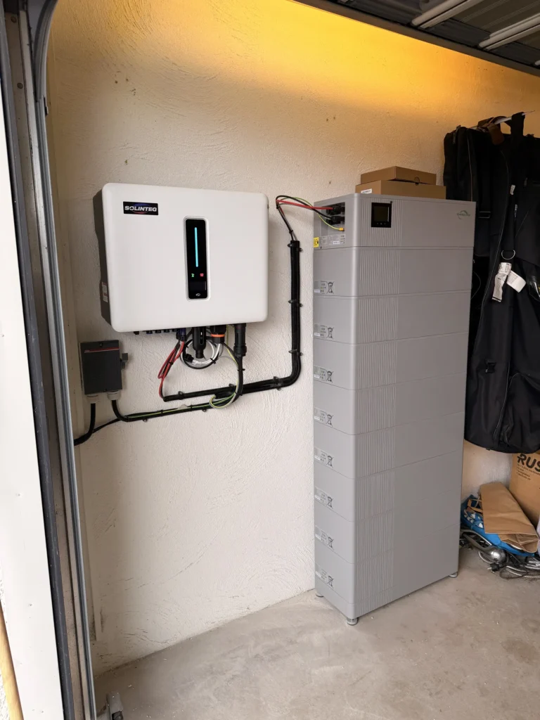 Färdig installation av en Solinteg växelriktare och ett stapelbart solcellsbatteri i ett garage.