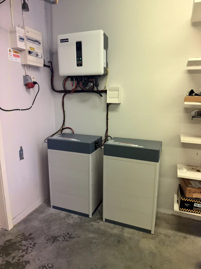 Färdig installation av en Solinteg växelriktare och två solcellsbatterier placerade på golvet inomhus