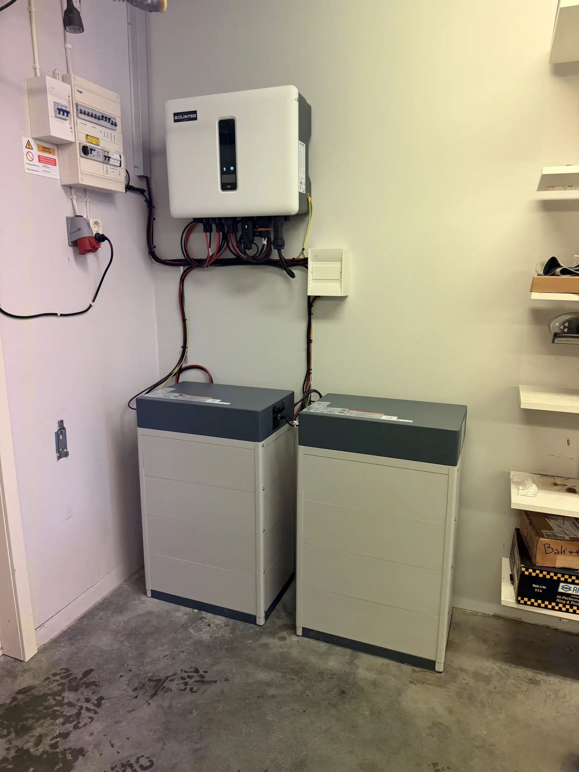 Färdig installation av en Solinteg växelriktare och två solcellsbatterier placerade på golvet inomhus
